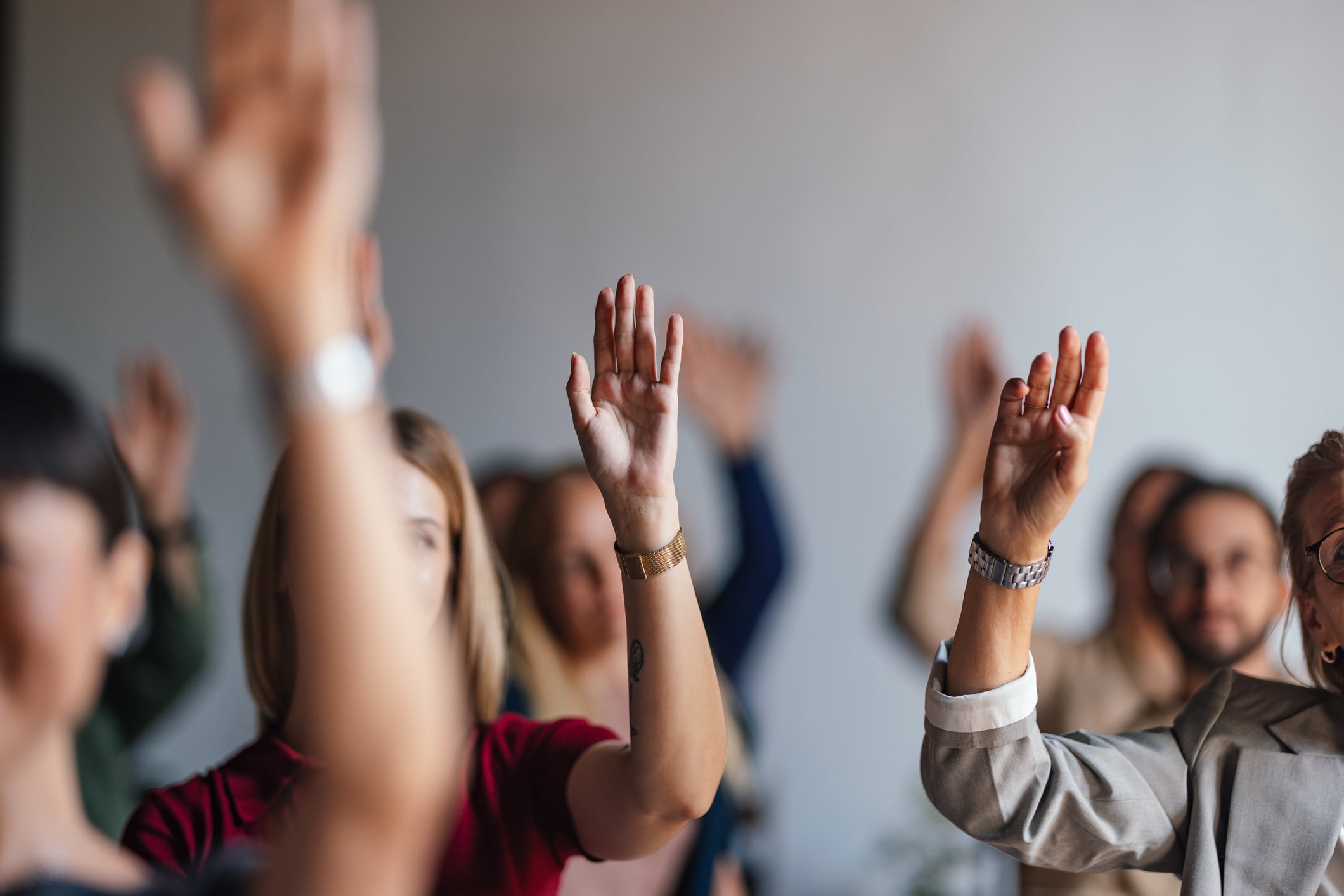 Group of adults with hands raised