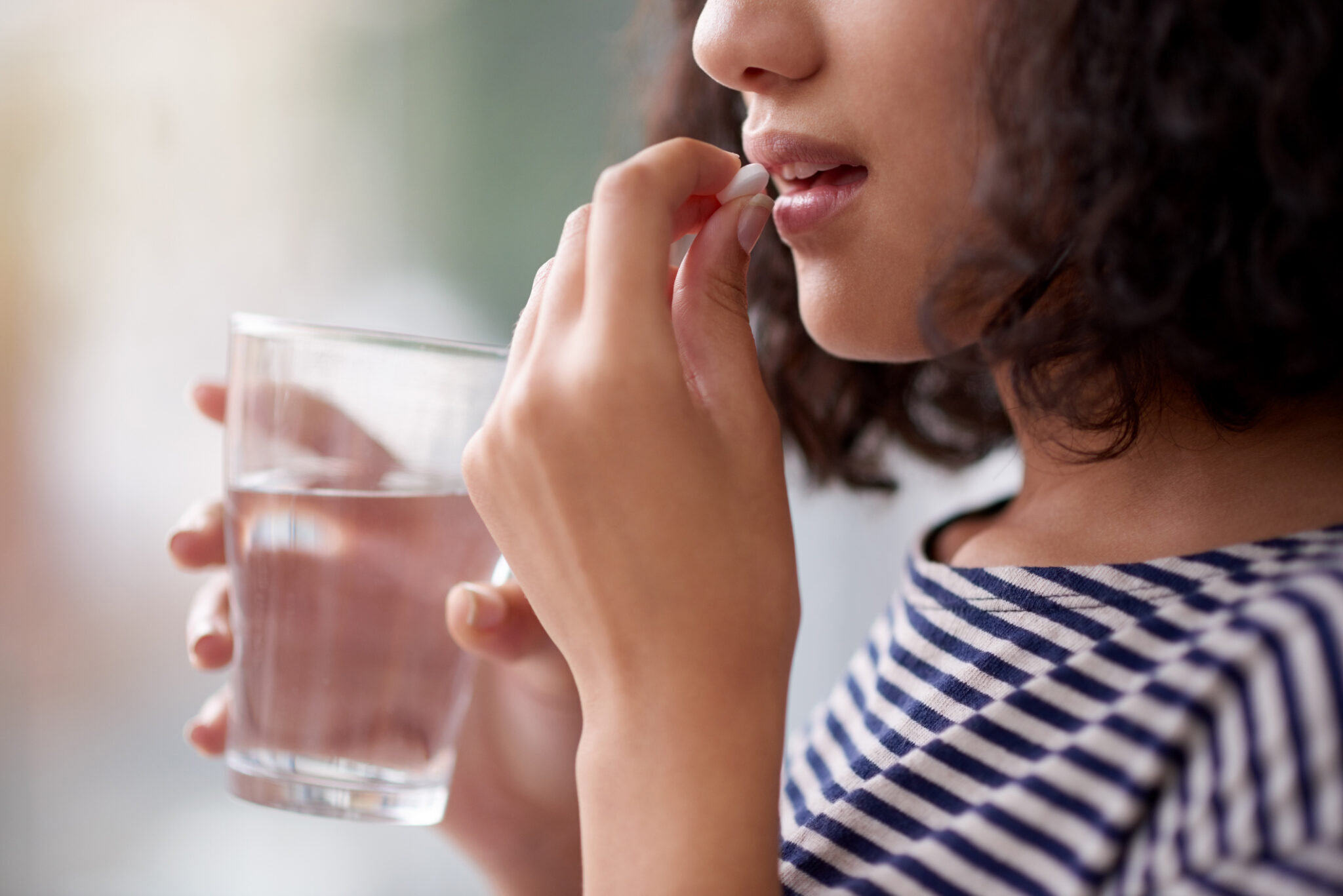 Women taking pill with water