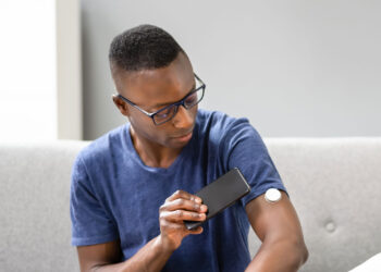 Man scanning a continuous glucose monitor with this smartphone device