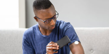 Man scanning a continuous glucose monitor with this smartphone device