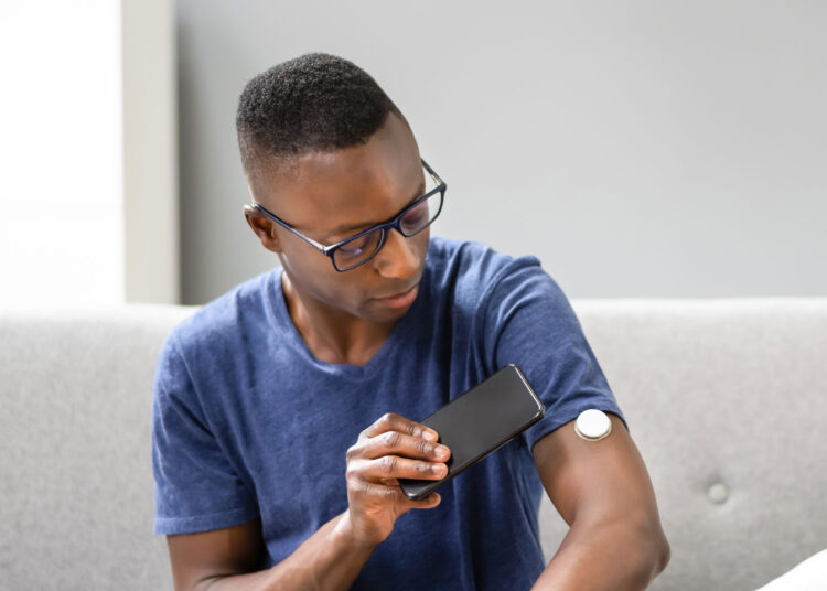 Man scanning a continuous glucose monitor with this smartphone device