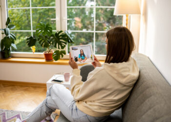 Image depicting a woman on the couch using her tablet for a virtual healthcare visit